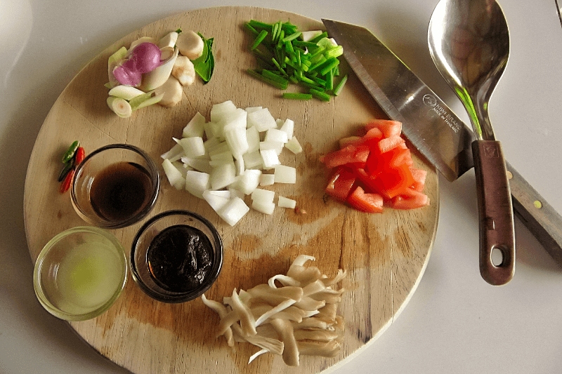 In der thailändischen Küche werden vor allem frische Zutaten verwendet. Holzbrett mit klein geschnittenen Zutaten